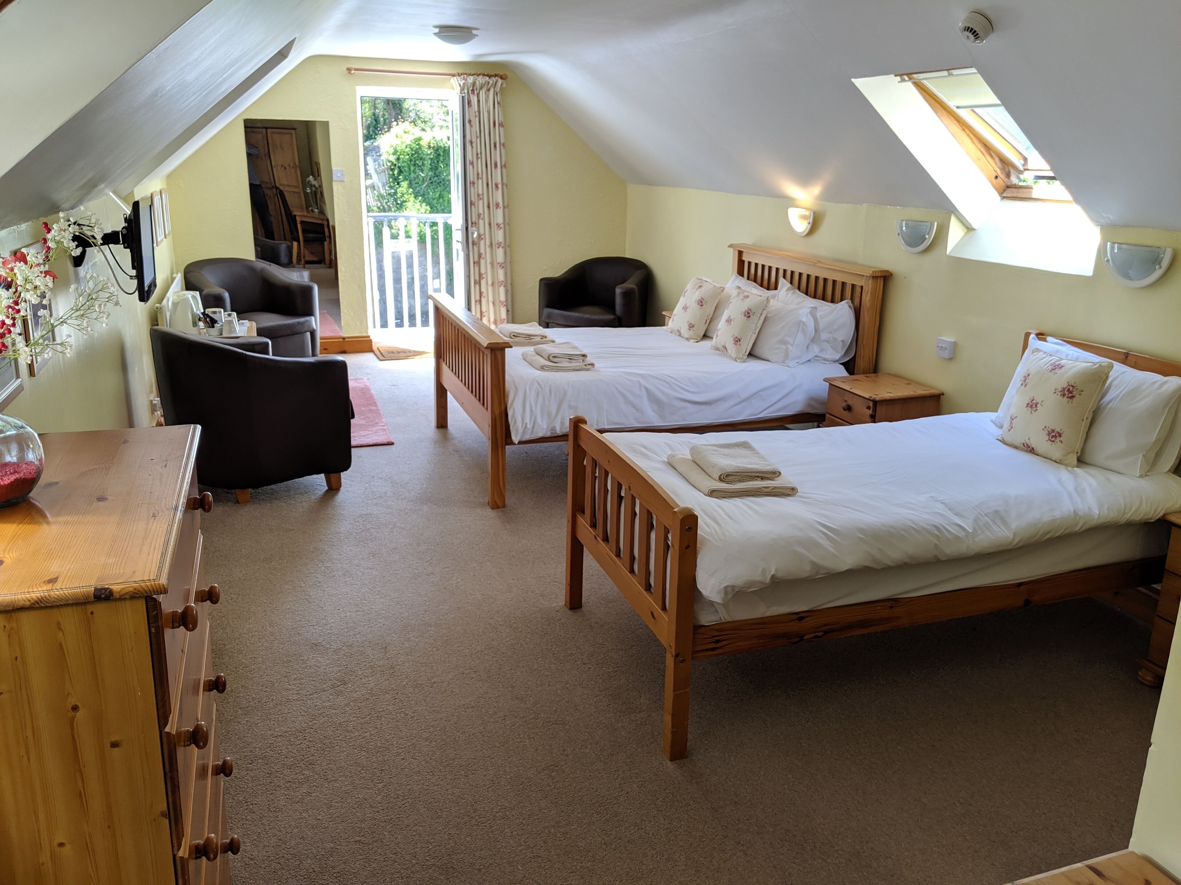 A cozy attic bedroom with two wooden beds, a desk, and a chair.