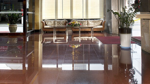 Um hall amplo com um lustre grande, área de estar com sofá e poltronas, e uma planta em vaso.