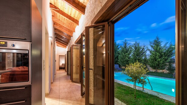 A modern kitchen with a built-in oven and a view of a swimming pool. - Astarte Villas - Kyveli Villa (Zakynthos)