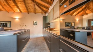 A modern kitchen with wooden beams, stainless steel appliances, and a central island. - Astarte Villas - Kyveli Villa (Zakynthos)