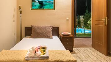 A hotel room with a bed, a nightstand, a framed picture of a bridge, and a view of an outdoor swimming pool.