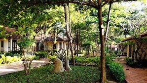 A courtyard with a pathway, trees, and a traditional building with a tiled roof. - Doi Su Resort (Tan Thanh)
