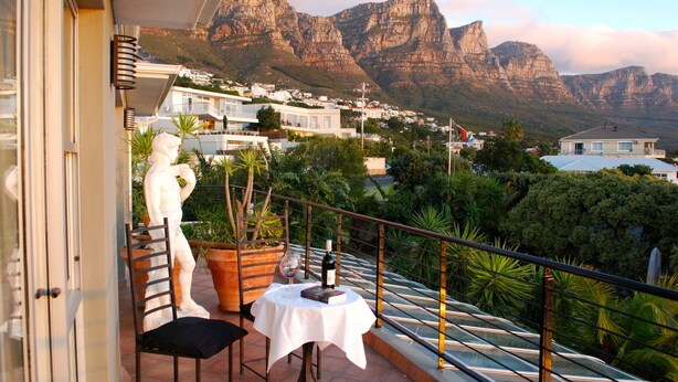 A balcony with a table, chairs, and a statue. - Villa Surprise (Cape Town)