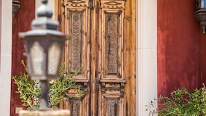 Una puerta de madera con tallas complejas y una lámpara de metal al frente.