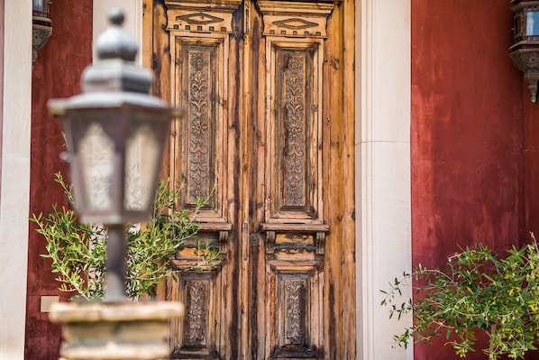 Une porte en bois ornée de sculptures complexes et une lampe en métal, placée au premier plan.