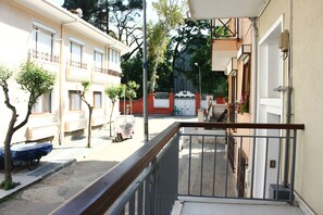 Una calle residencial con una entrada porticada, una patineta y una bicicleta.