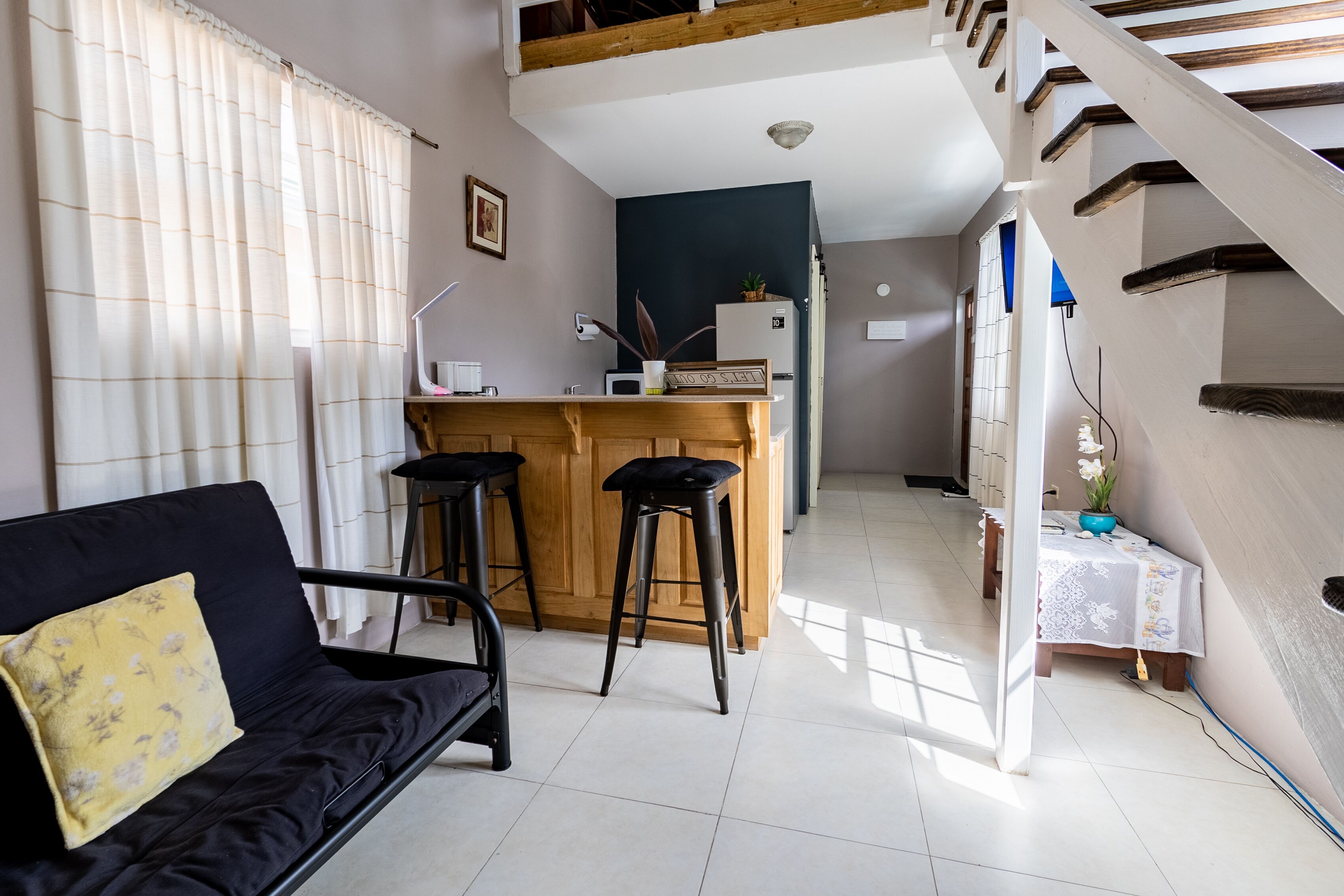 Un espacio habitable compacto con sofá, una pequeña cocina y una escalera.