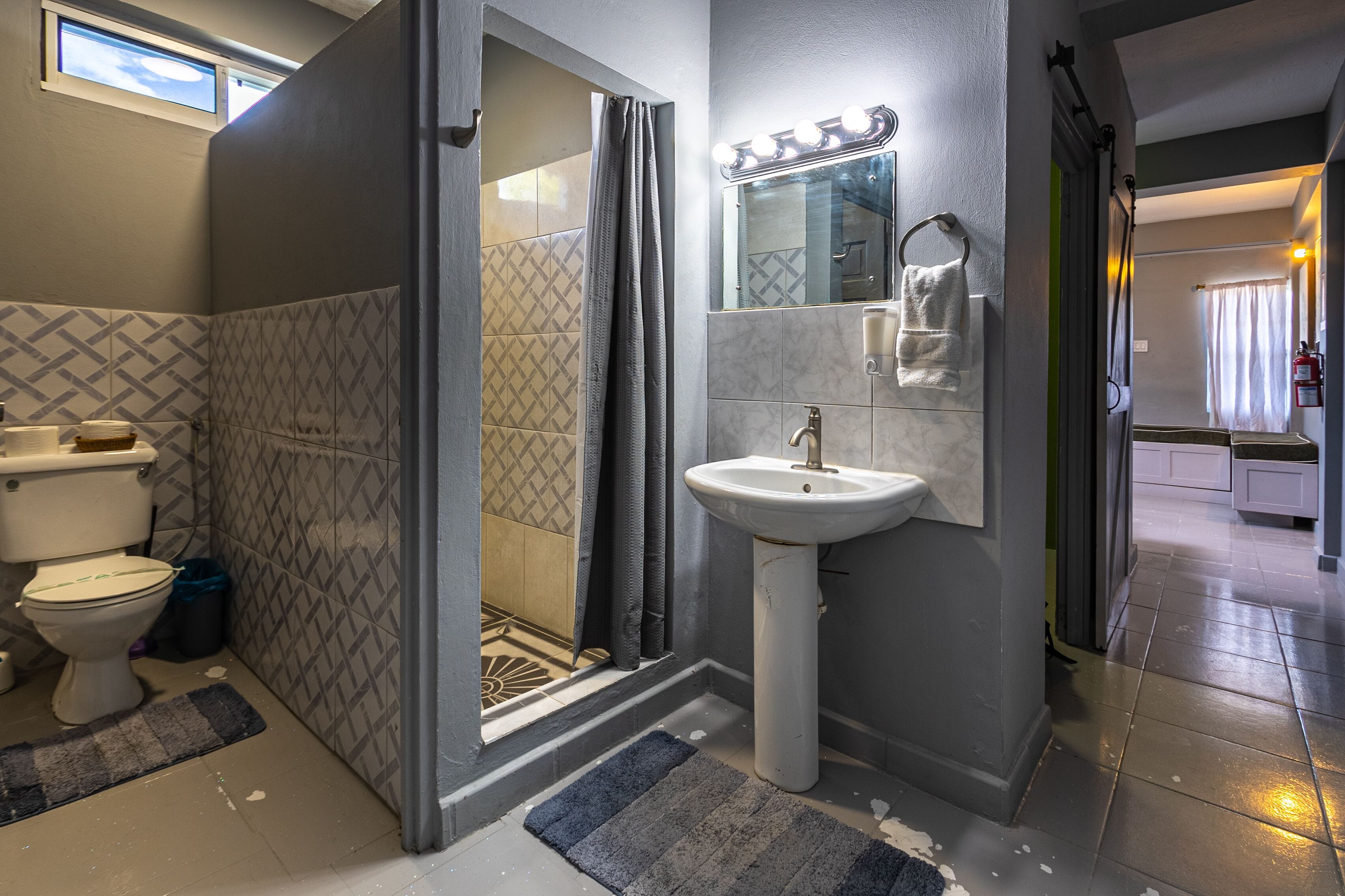 A bathroom with a shower, toilet, sink, and vanity mirror.