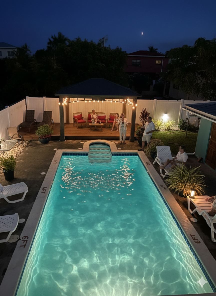 A rectangular swimming pool with clear water, surrounded by lounge chairs and a covered seating area with string lights.