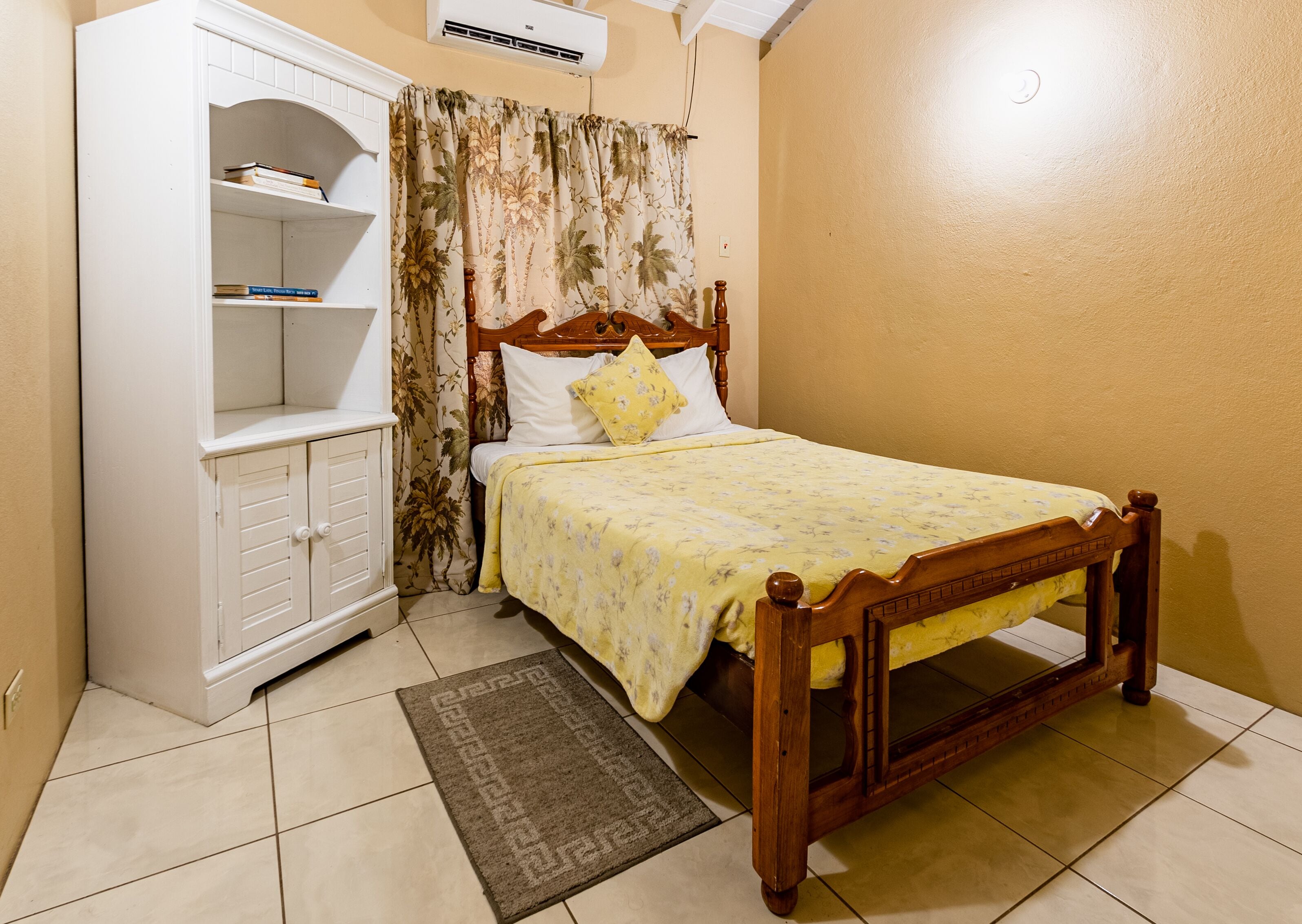A bedroom with a wooden bed, a white wardrobe, and a small shelf unit.