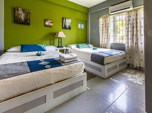 A hotel room with two beds, a nightstand, a lamp, and artwork on the walls.