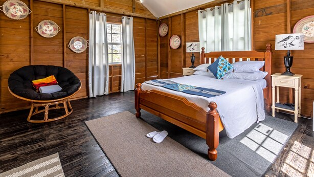 A wooden-paneled bedroom with a bed, a chair, and a nightstand.