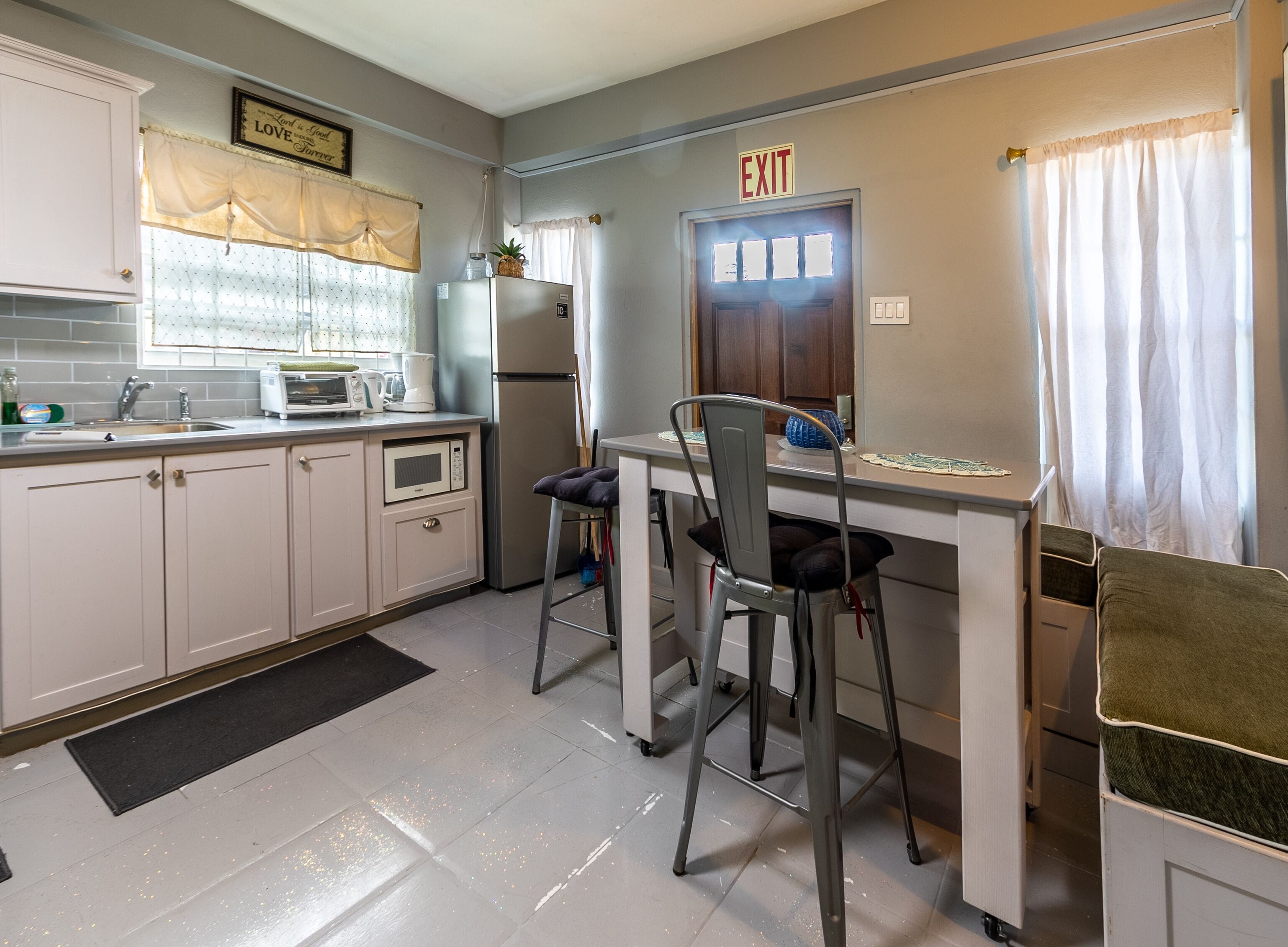 A kitchen with a dining area, an exit sign, and a refrigerator.