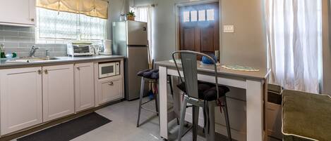 A kitchen with a dining area, an exit sign, and a refrigerator.
