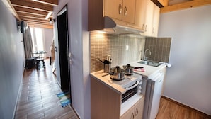 A compact kitchen with wooden cabinets, a stove, and a sink. - Argo Maisonettes & Suites (Lefkada)