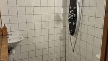 A small bathroom with a shower, toilet, and sink.