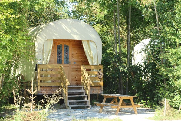 A wooden cabin with a covered entrance, a wooden staircase, and a picnic table.