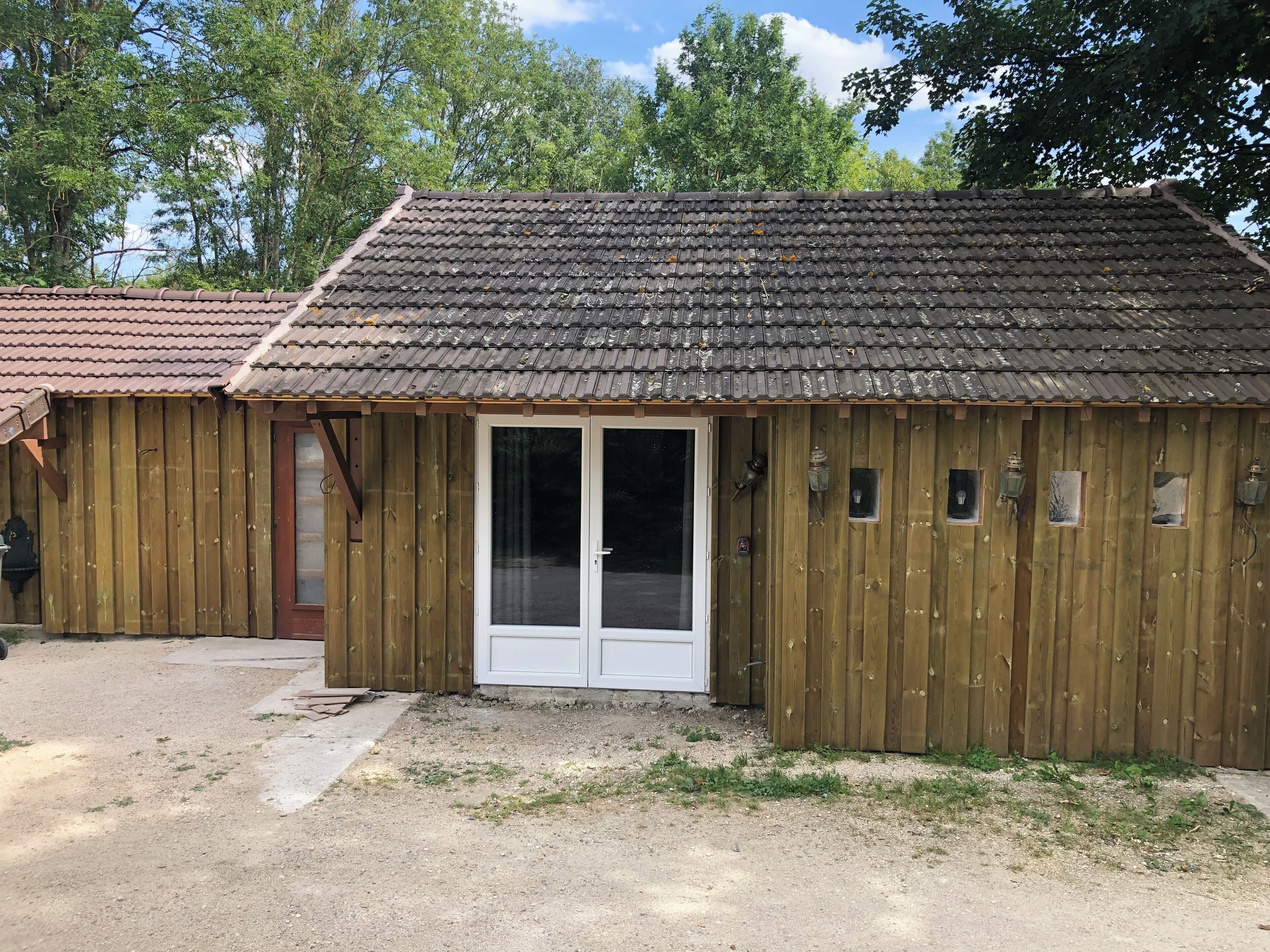 A wooden building with a tiled roof, a sliding glass door, and small windows.