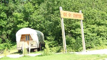 Un panneau en bois sur lequel on peut lire « OG CUSTER », une structure en bois abritée et un paysage boisé en arrière-plan.