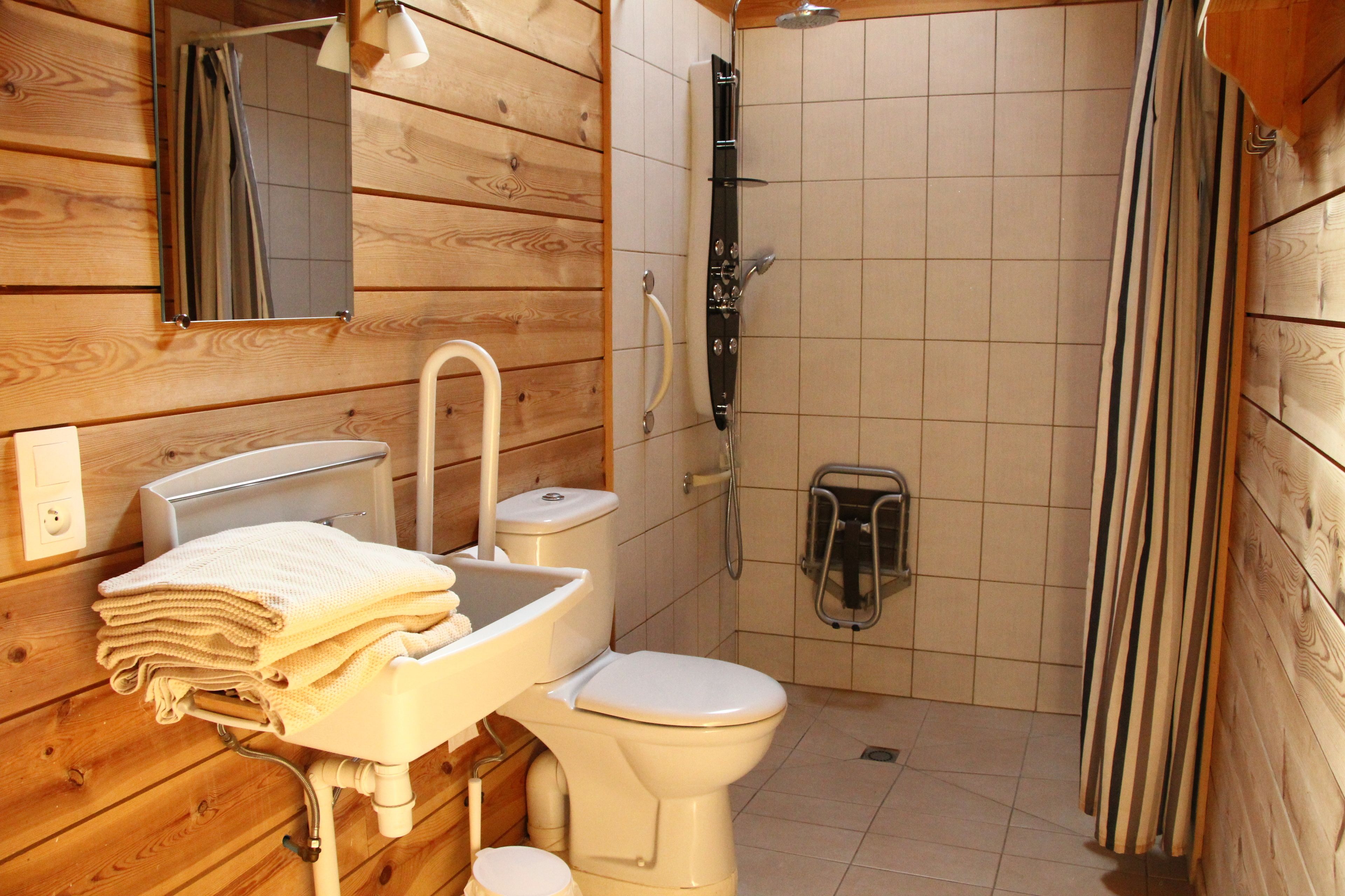 Une salle de bain rustique, aménagée dans une cabane en bois, avec un lavabo, des toilettes et une douche.