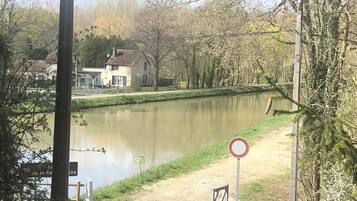 Une rivière, avec des maisons d’un côté et un panneau indiquant l’interdiction d’accès de l’autre.