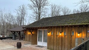 Eine Holzhütte mit einem Ziegeldach, einer Tür und vier Fenstern mit Wandleuchten.