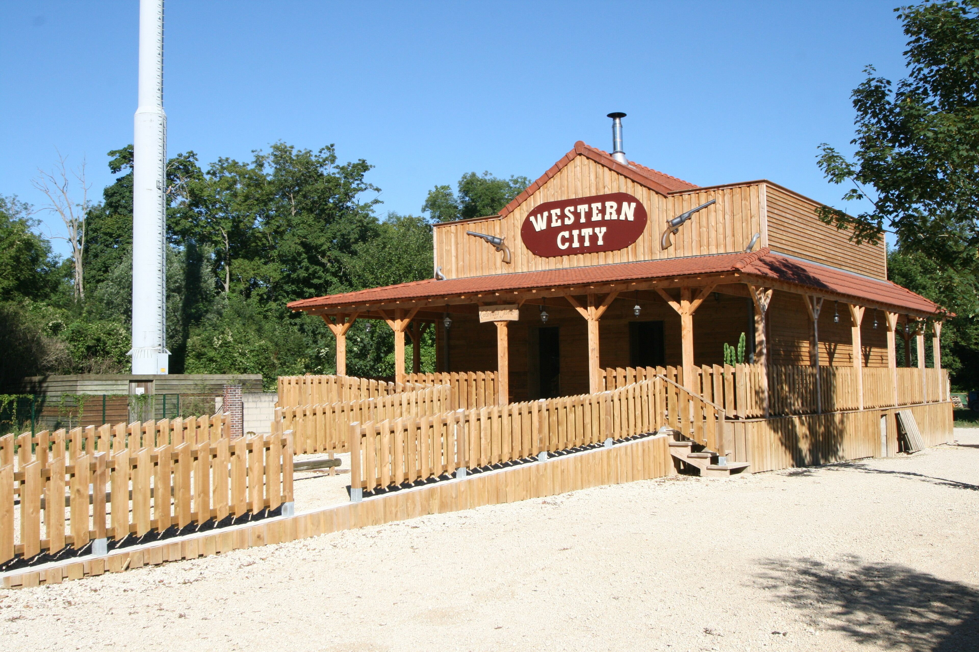 Ein Gebäude im Western-Stil mit Holzfassade, einem Schild mit der Aufschrift "Western City" und einem hölzernen Zaun davor.
