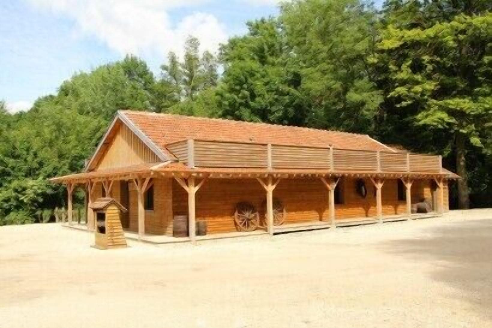 Un bâtiment en bois doté d’un porche et d’une brouette.