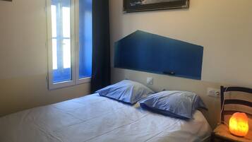 Un dormitorio con cama, ventana, calentador de pared y un cuadro.