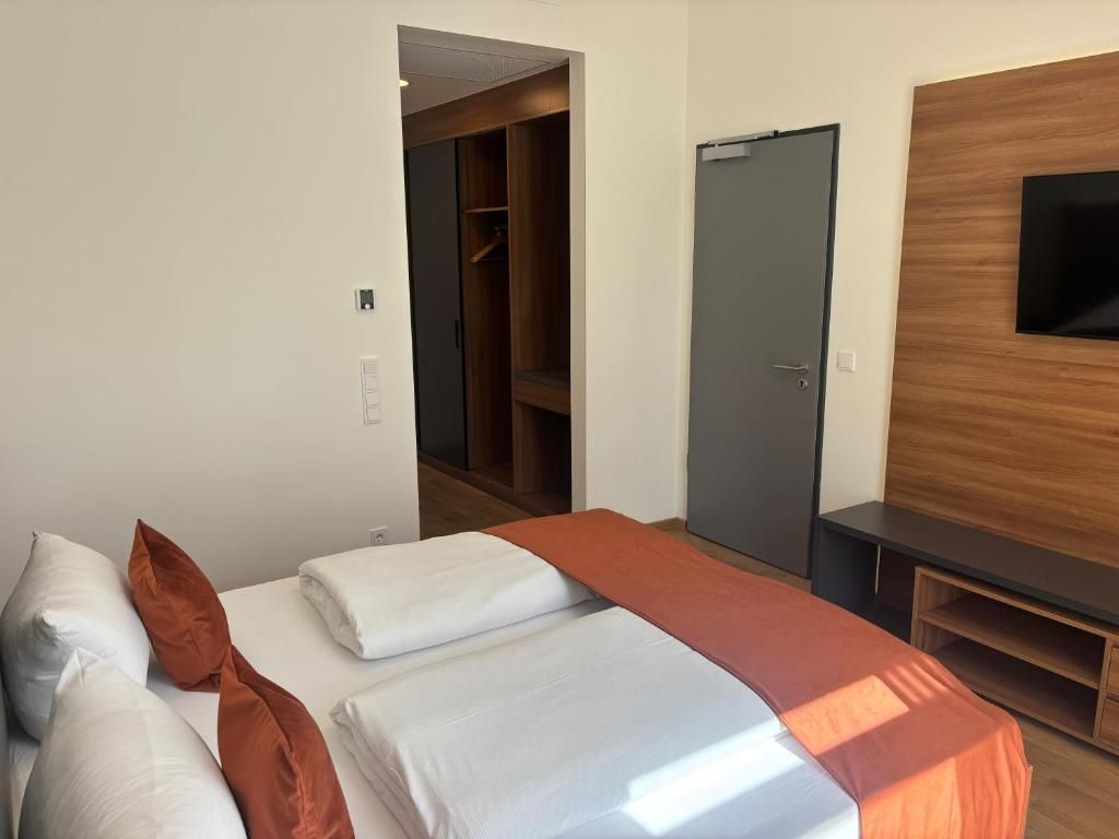 Una habitación de hotel con una cama, un armario, un televisor y una puerta.