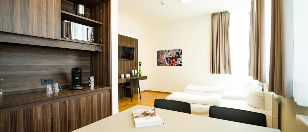Ein modernes Hotelzimmer mit einem Holzkasten, einem Esstisch, einer Couch und einem Bild an der Wand.