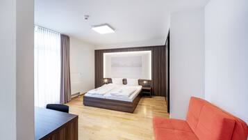 Een moderne hotelkamer met een groot bed, een bureau en een rode bank.