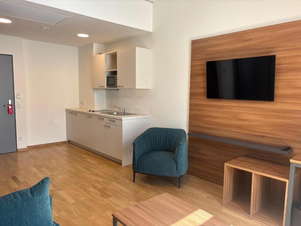Un interior moderno con cocina, zona de estar y televisor montado.