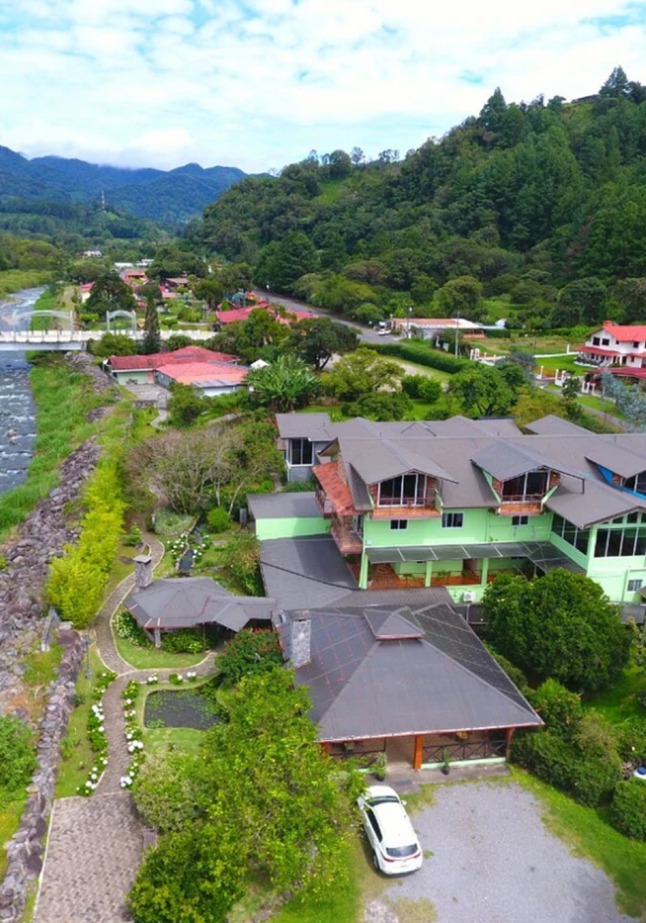 A residential area with houses, a river, and a mountainous backdrop.