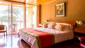Une chambre à coucher comprenant un lit, une chaise, une table de chevet, une lampe fixée au mur et une fenêtre avec des rideaux.