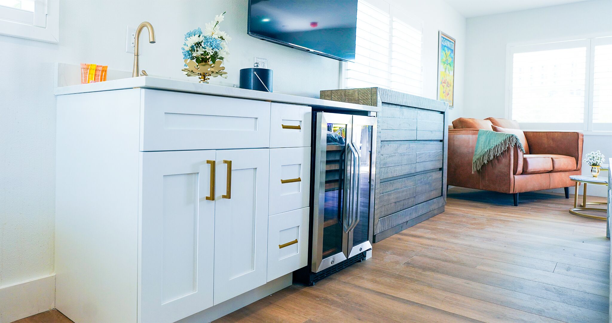 A modern kitchen with white cabinetry, a built-in refrigerator, and a wooden accent wall.