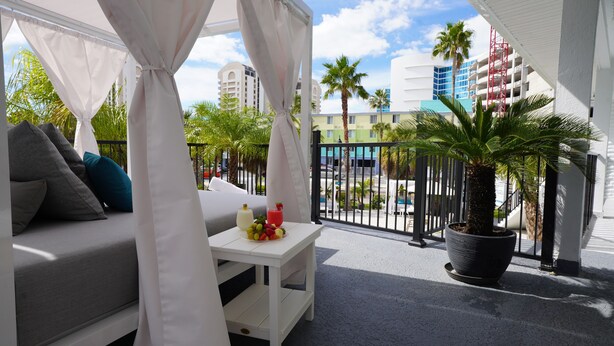 A balcony with a white sofa, a small table with drinks, and a potted plant. - Ivory Sands Beach Suites (Clearwater Beach)