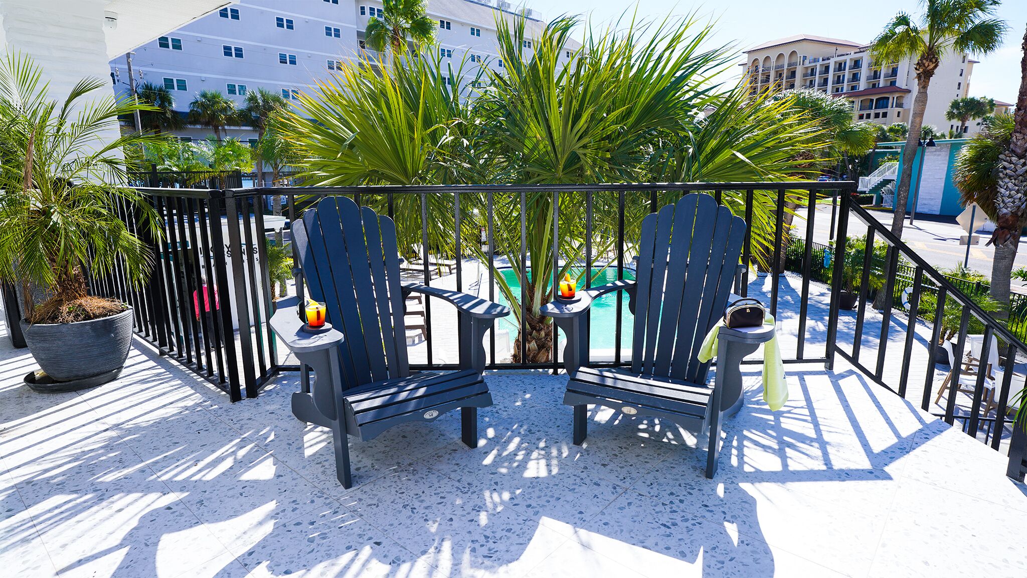 A balcony with two Adirondack chairs, a small table, and a potted plant.