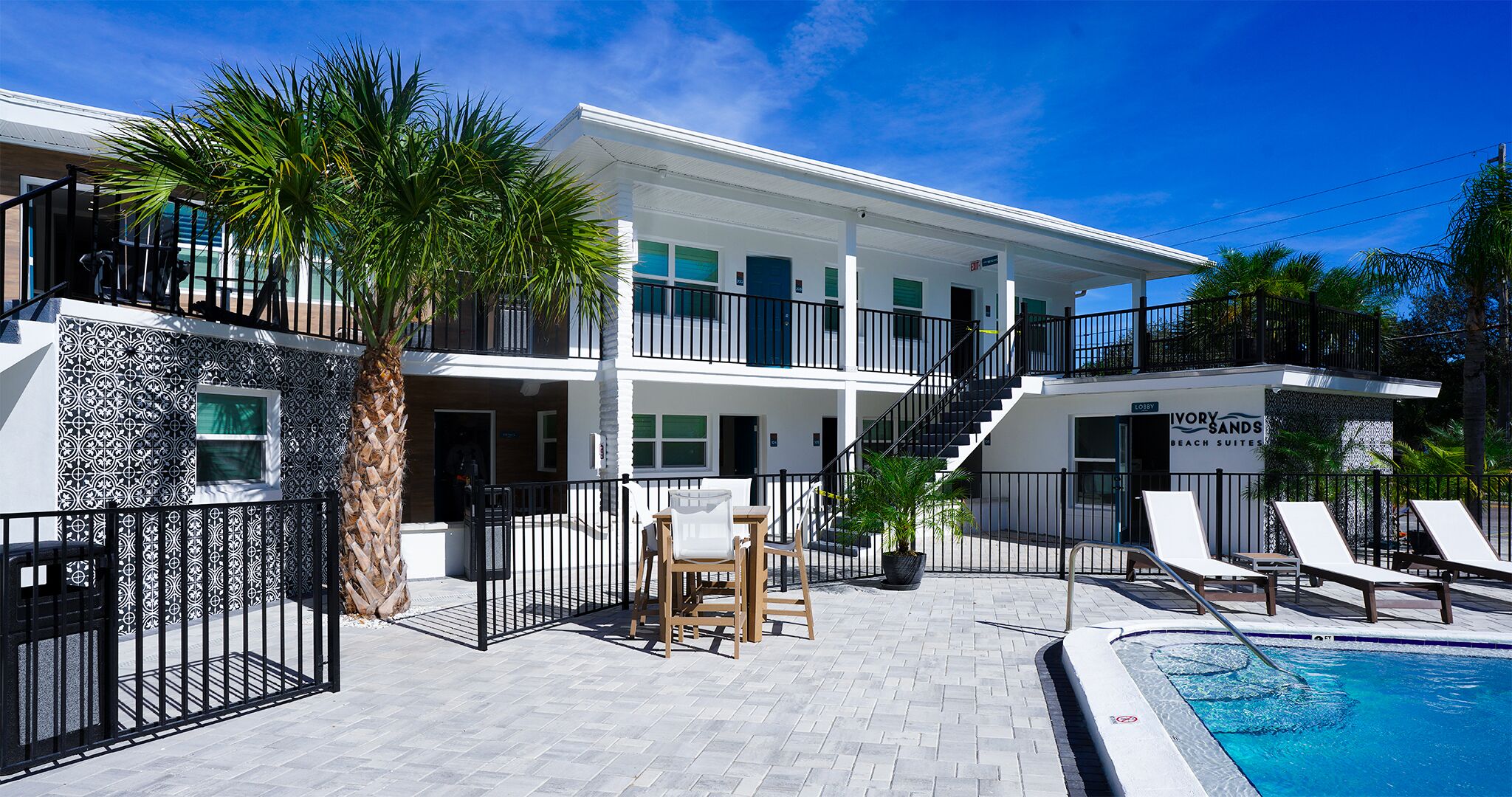 A hotel with a pool, outdoor seating, and a sign for 'Lobster Beach Suites'.