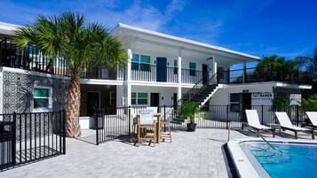 A hotel with a pool, outdoor seating, and a sign for 'Lobster Beach Suites'.