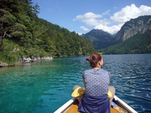 A woman in a boat on a calm lake with mountains in the background. - Hotel Bavaria (Oberstaufen)