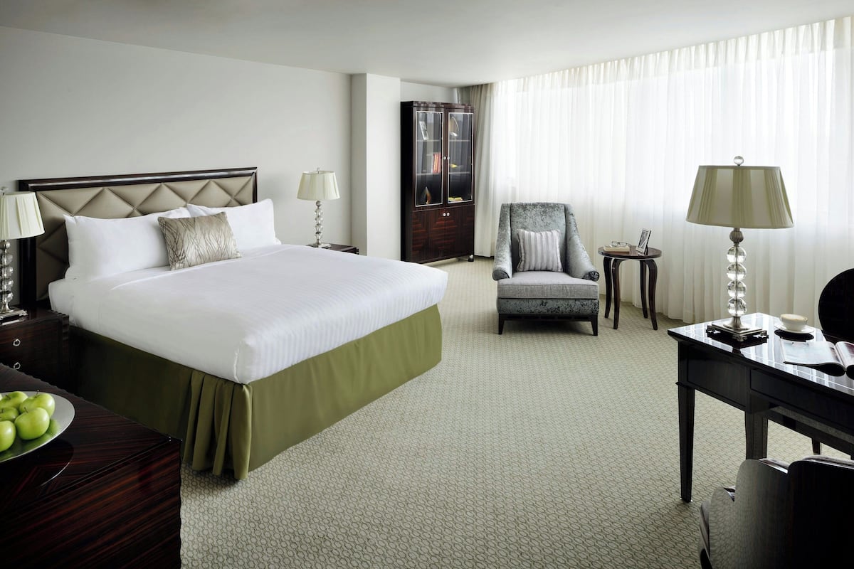 Une chambre d’hôtel avec un grand lit, une chaise, un bureau et une armoire.