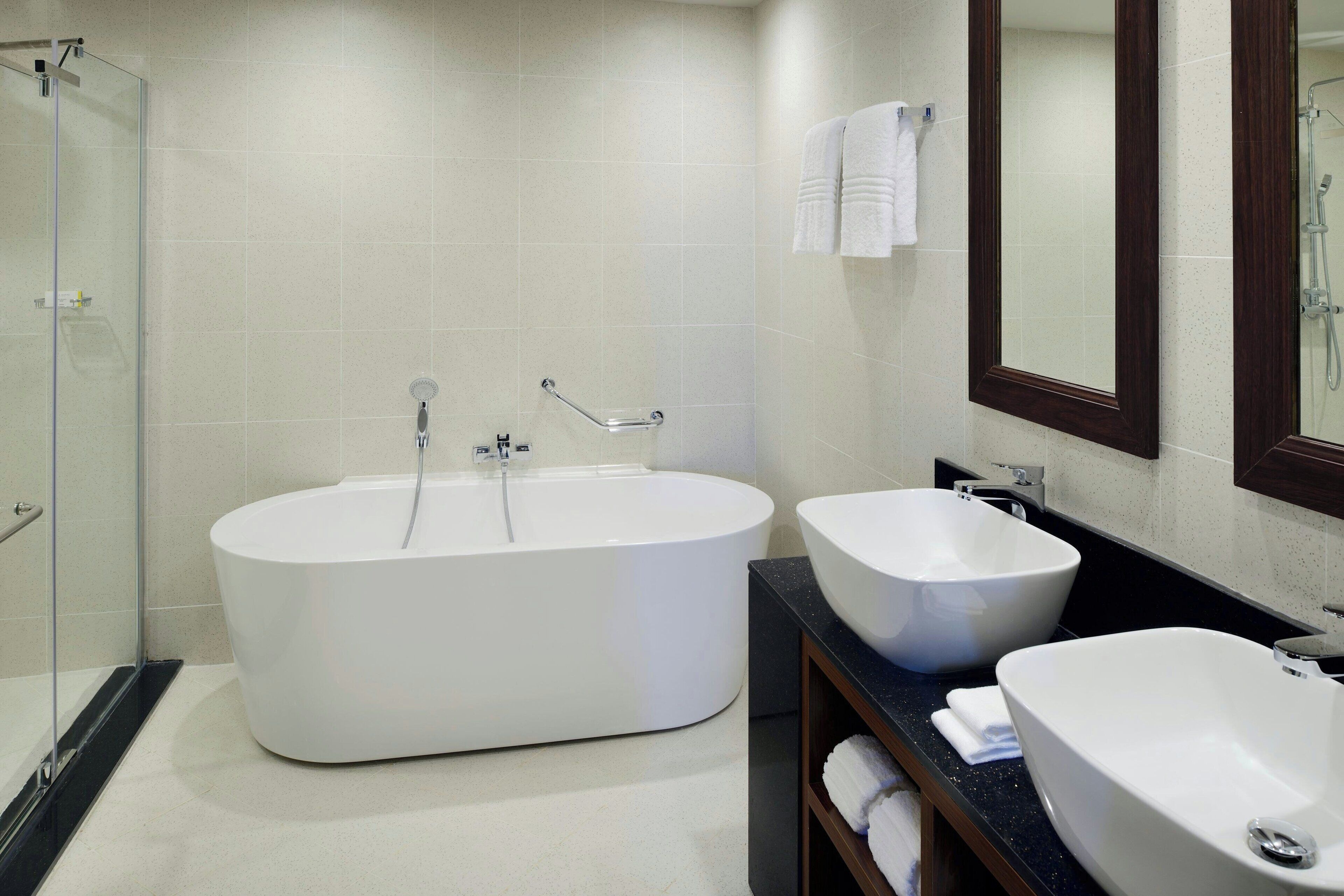 Un baño moderno con una bañera independiente, dos lavamanos, una cabina de ducha de vidrio y un espejo grande.