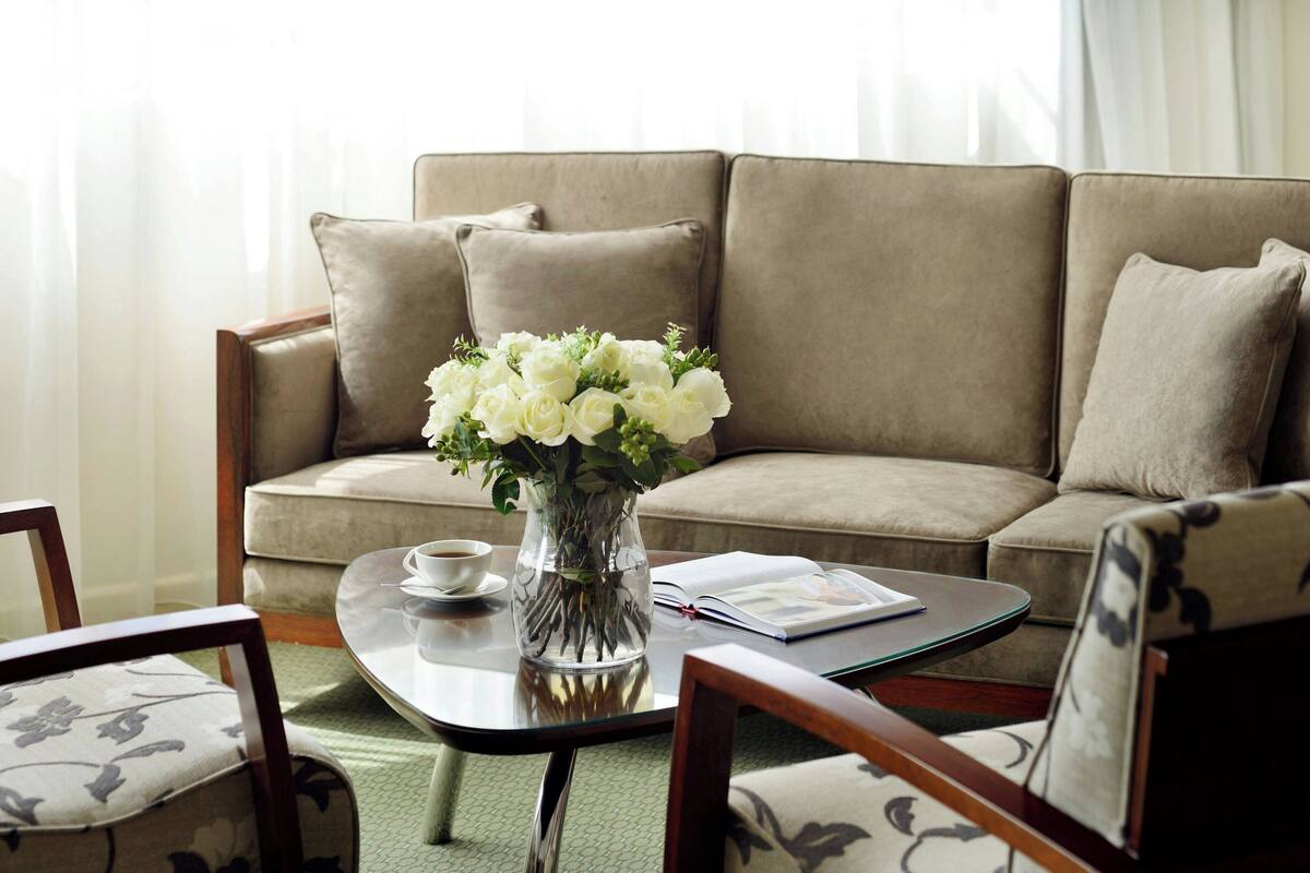 Un salon avec un canapé, une table basse, un vase de fleurs et un livre.