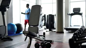 Et fitnessrum med træningsudstyr, løbebånd og en person, der bruger et træningsapparat.