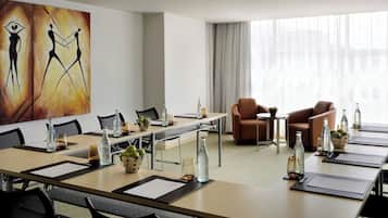 Un salón de conferencias con una larga mesa, sillas y un cuadro en la pared.