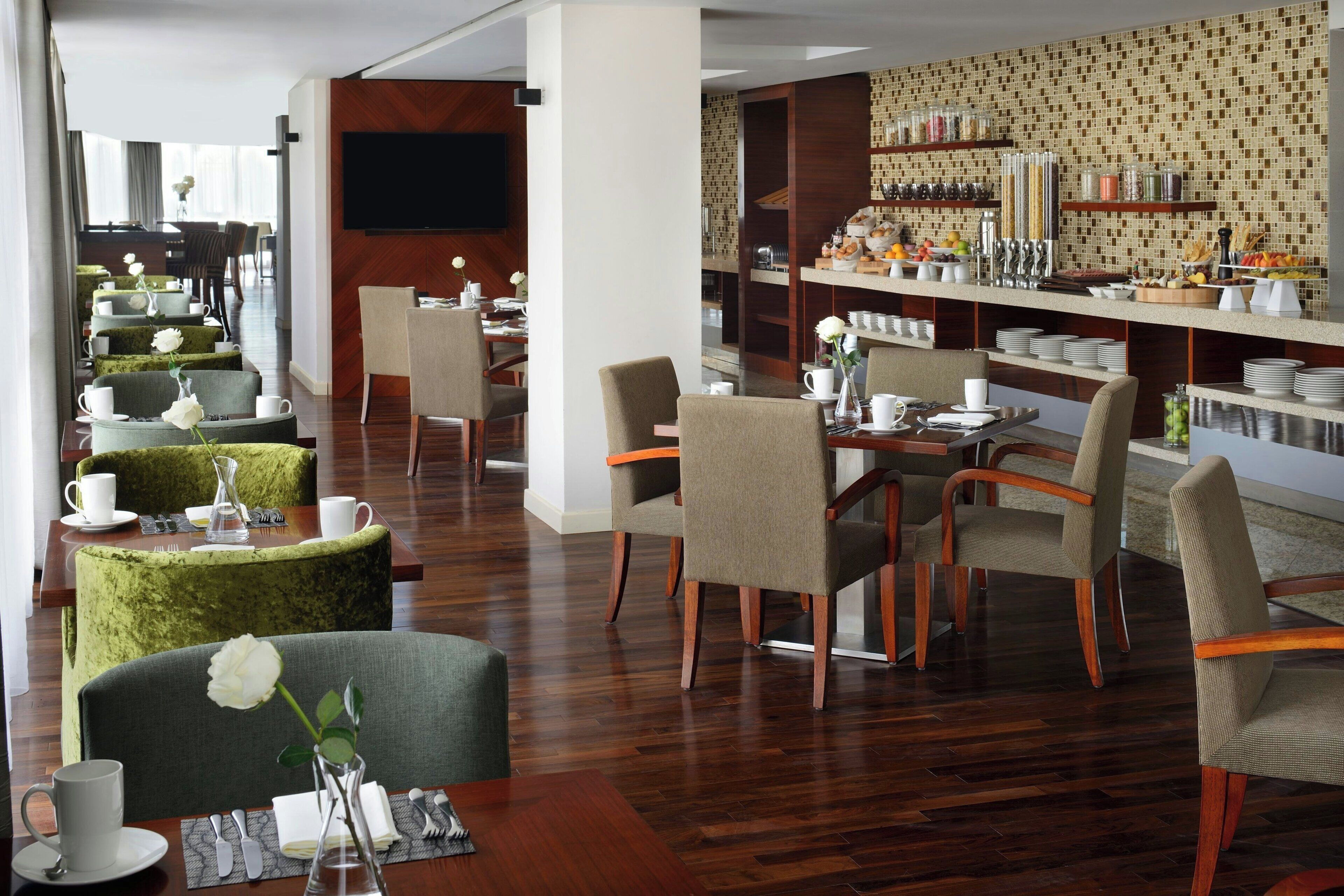A hotel dining area with multiple tables, chairs, and a buffet setup.