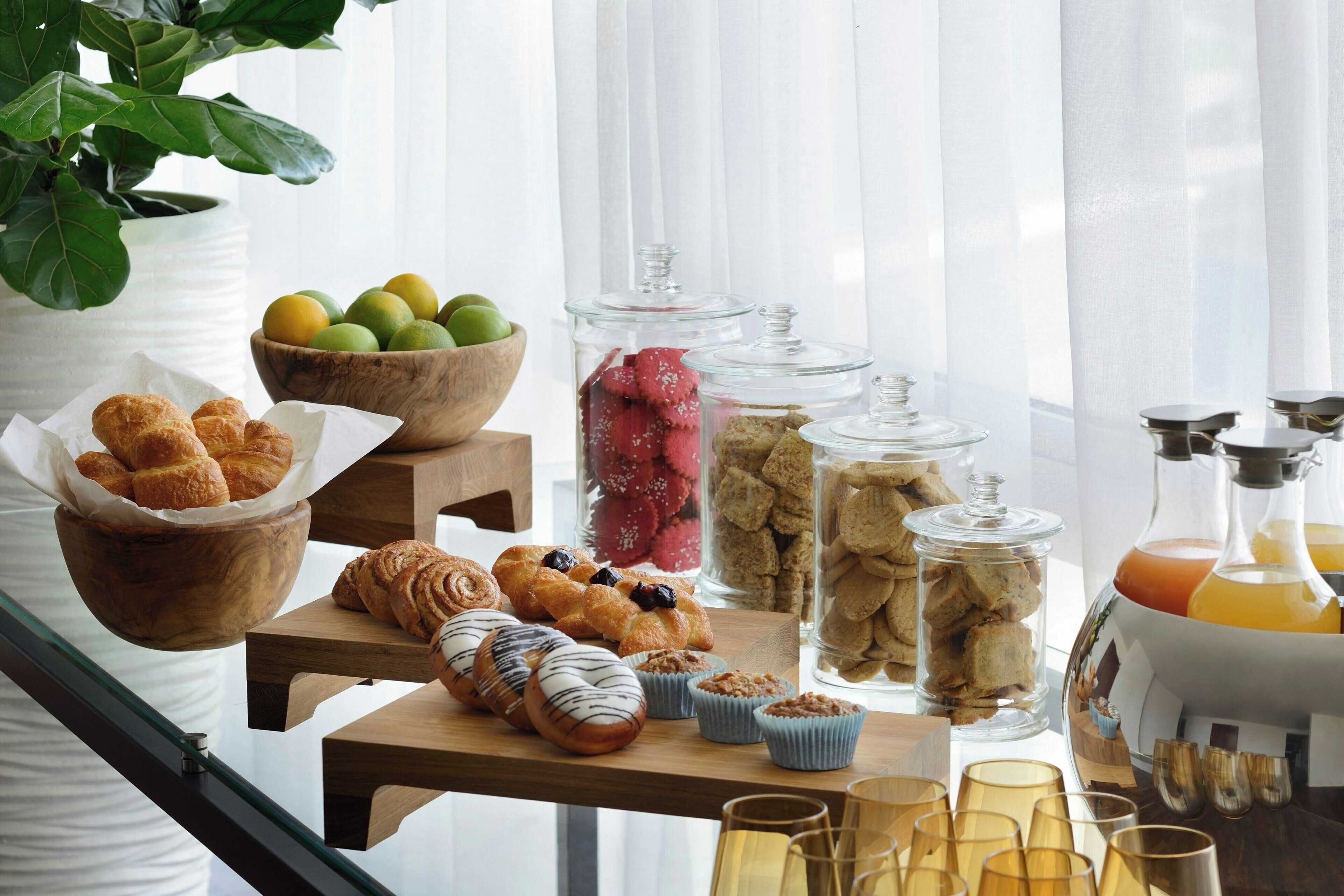 A breakfast buffet with pastries, fruits, and beverages.