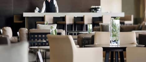 A modern hotel lobby with a central reception desk, comfortable seating areas, and a decorative vase with a plant.