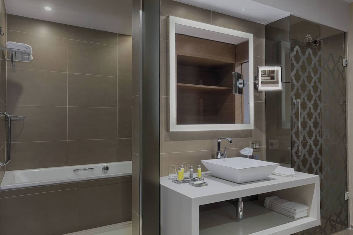 A modern bathroom with a bathtub, a large mirror, a sink, and a glass shower enclosure.